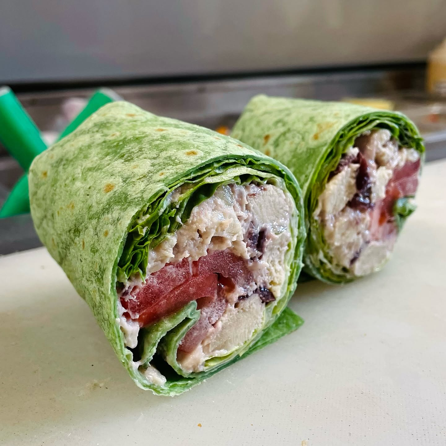 Daily Specials at Cravin’ Market & Deli chicken salad spinach wrap on deli cutting board
